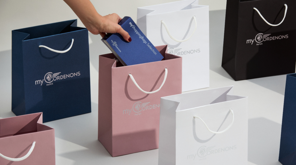 Personne qui dépose un nuancier myShoppingBags Selection dans un shopping bag myCordenons